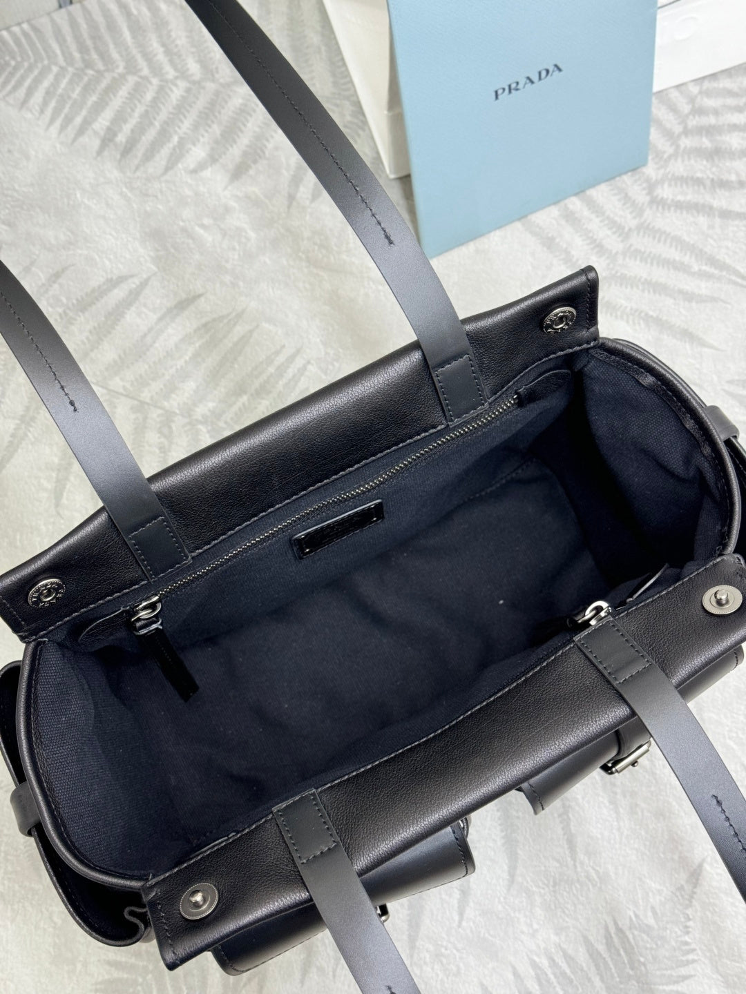 Prada black leather bag opened to show dark lining and inner pocket