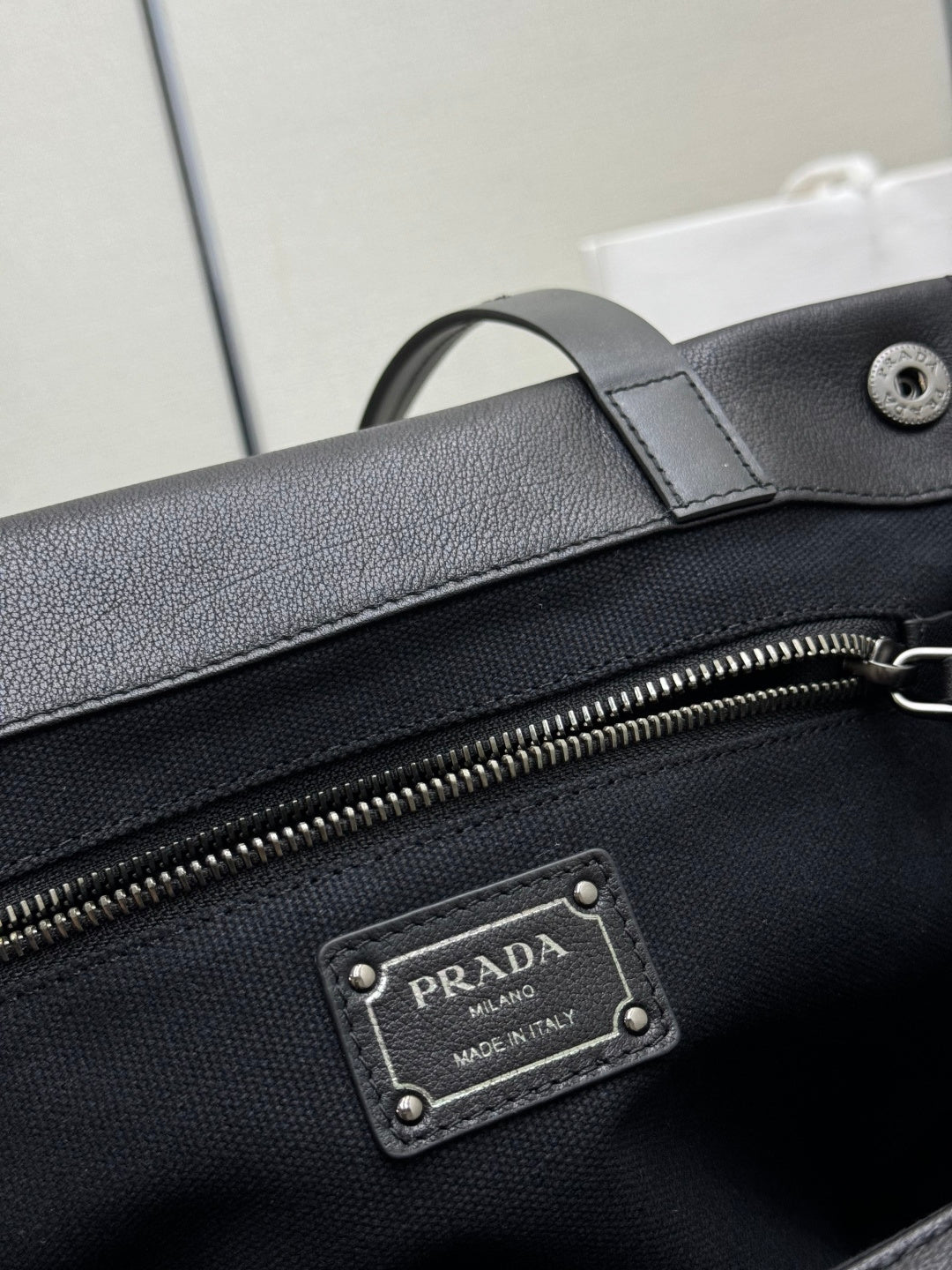 Prada Milano leather patch label on black bag beside zipper hardware