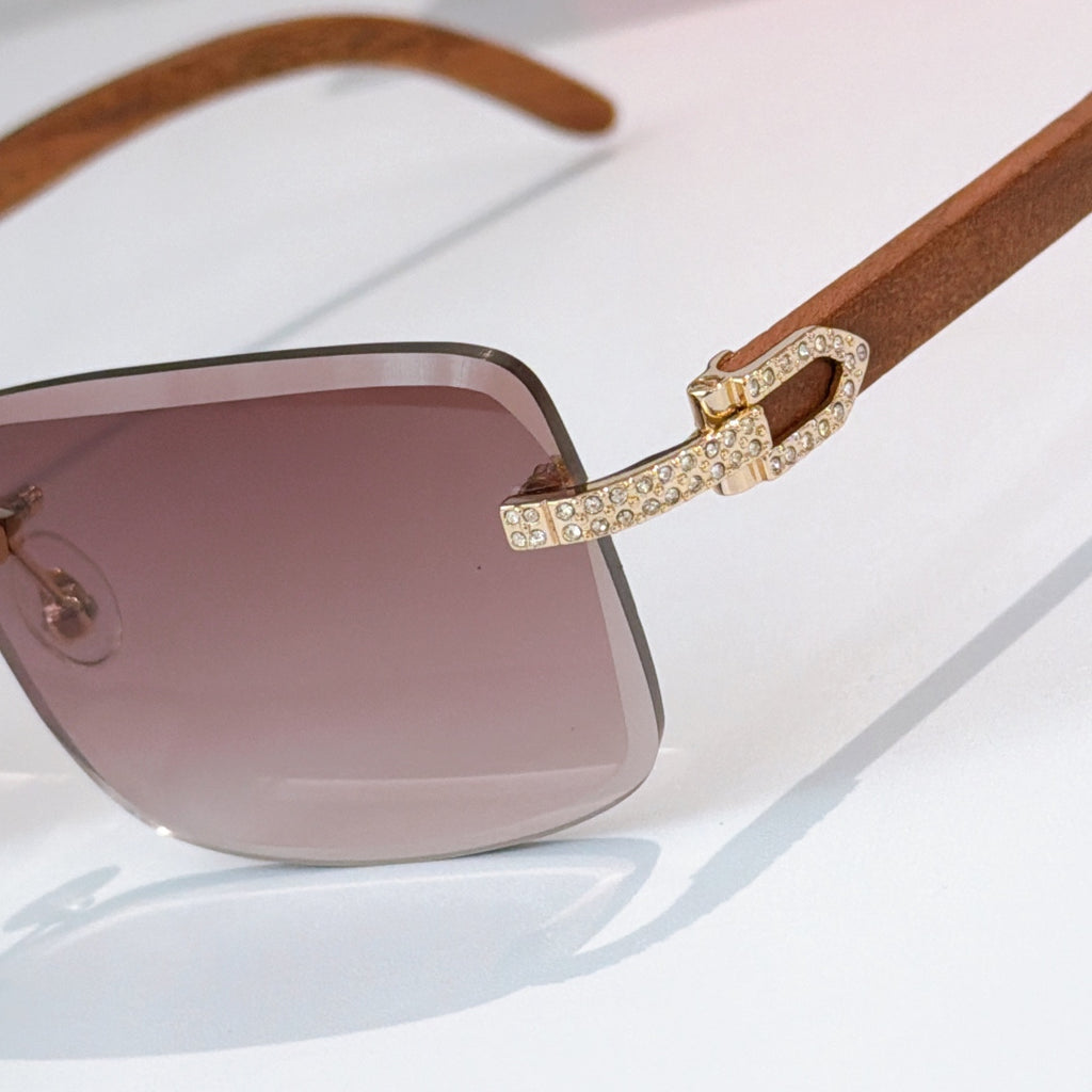 Close-up of square sunglasses with brown-tinted gradient lens and gold rhinestone bridge