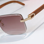 Close-up of square sunglasses with brown-tinted gradient lens and gold rhinestone bridge