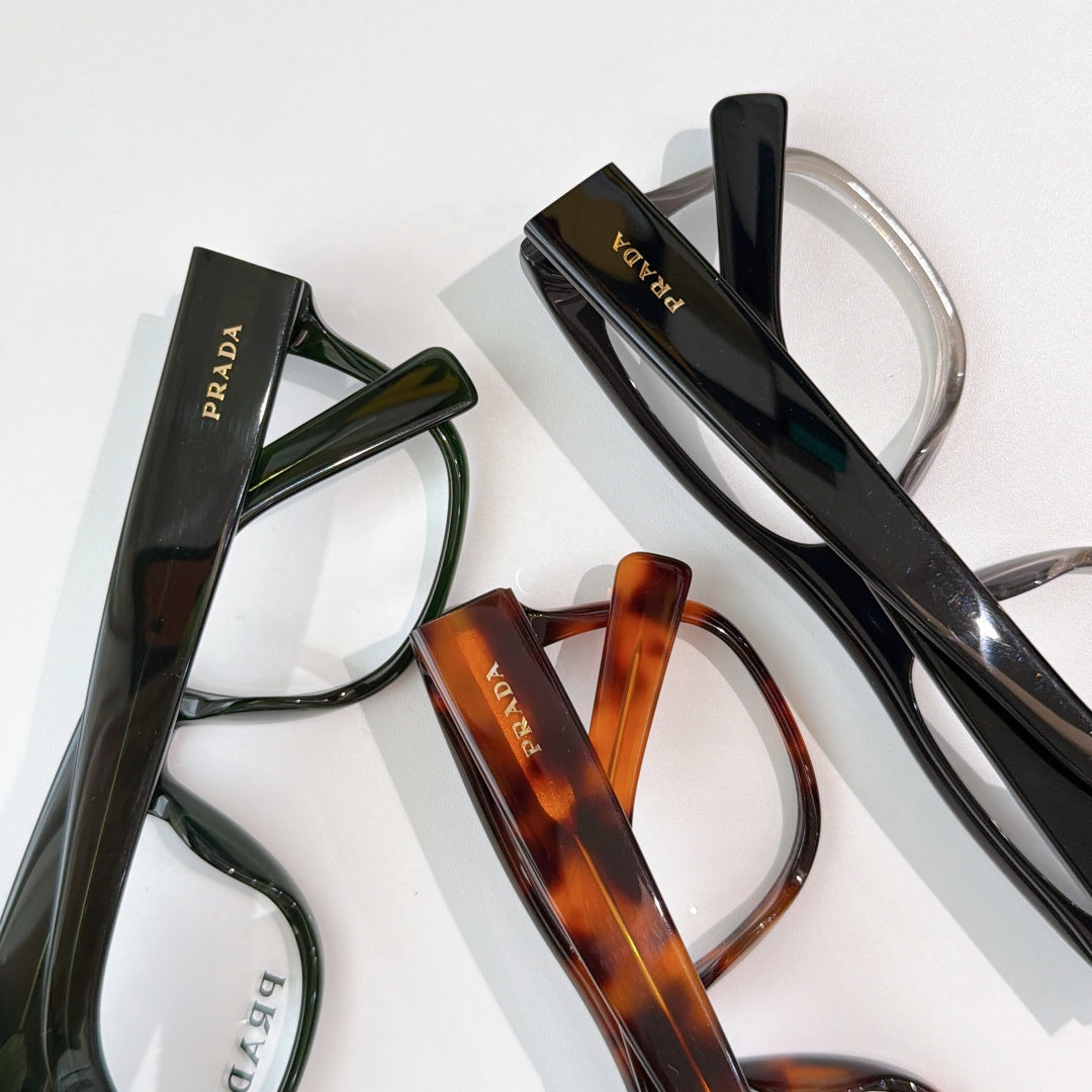 Prada eyeglasses assortment with black, green, and tortoiseshell frames, clear lenses