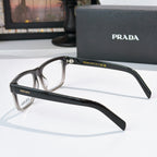 Prada black eyeglasses, side profile with temple logo and clear lenses.