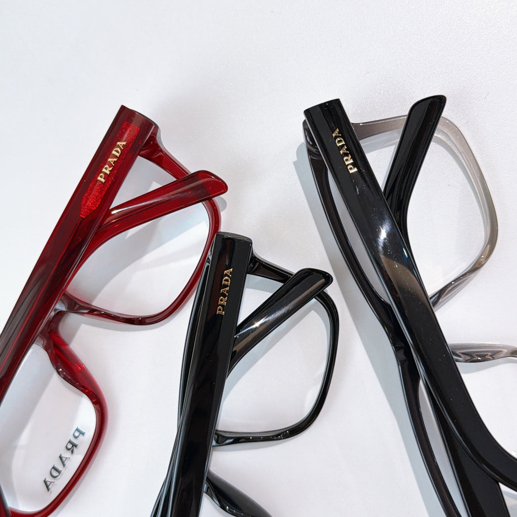 Prada eyeglasses set with red and black frames, clear lenses.