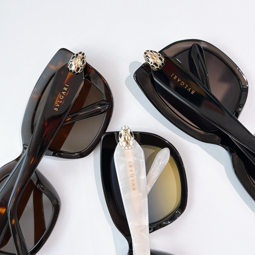 Sunglasses close-up with black frames and dark lenses, gold logo detail