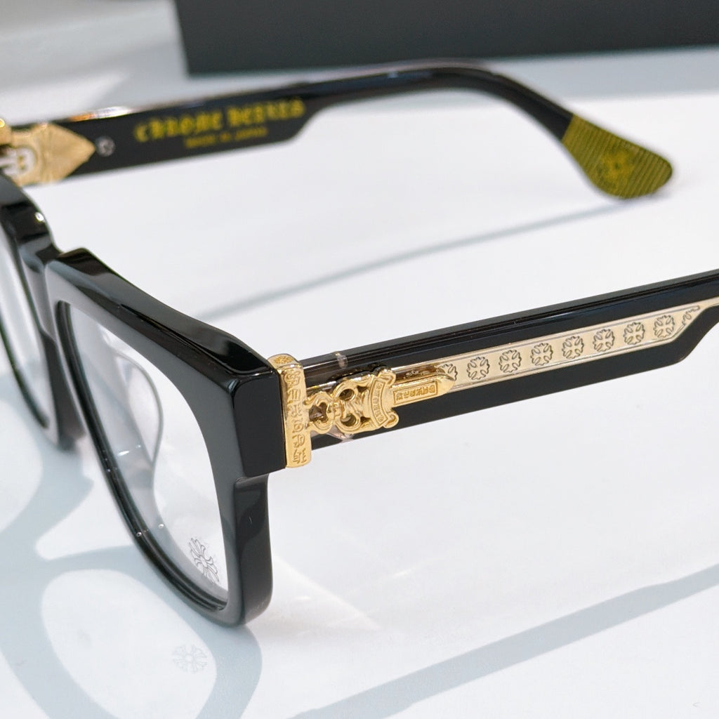 Close-up of black square eyeglass frame with gold-toned decorative temple bar
