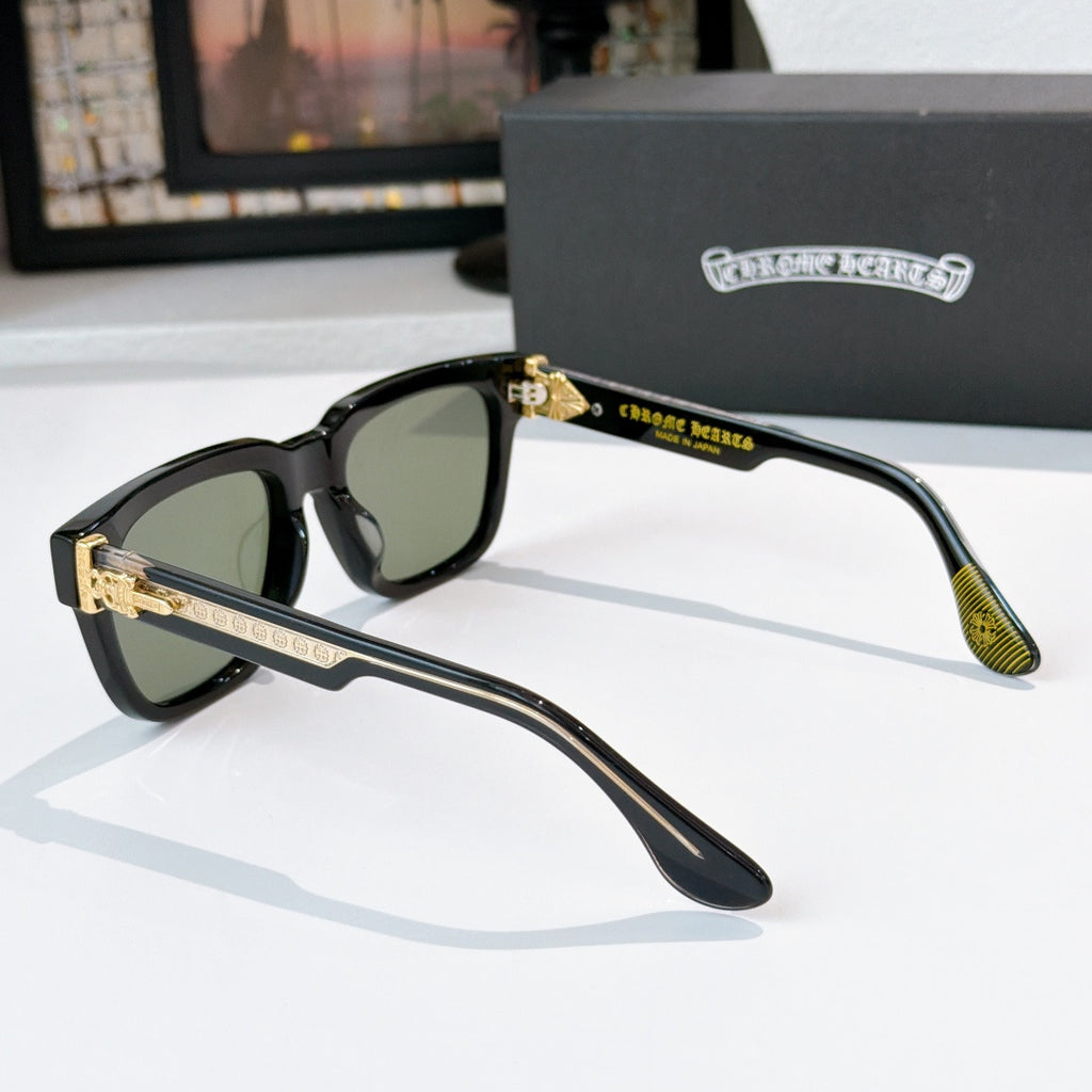 Black sunglasses side view with green lenses and gold accent temples