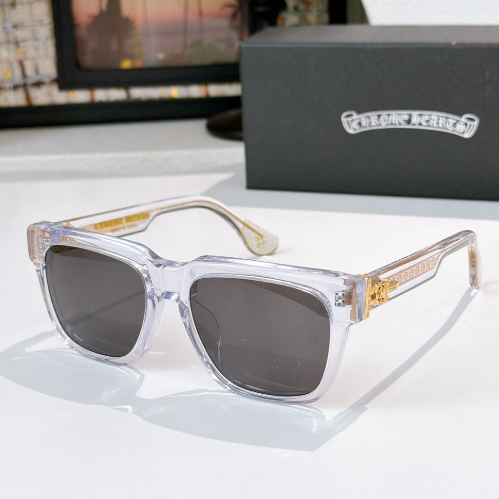 Smoke-tinted sunglasses with clear frames and gold side emblem detail
