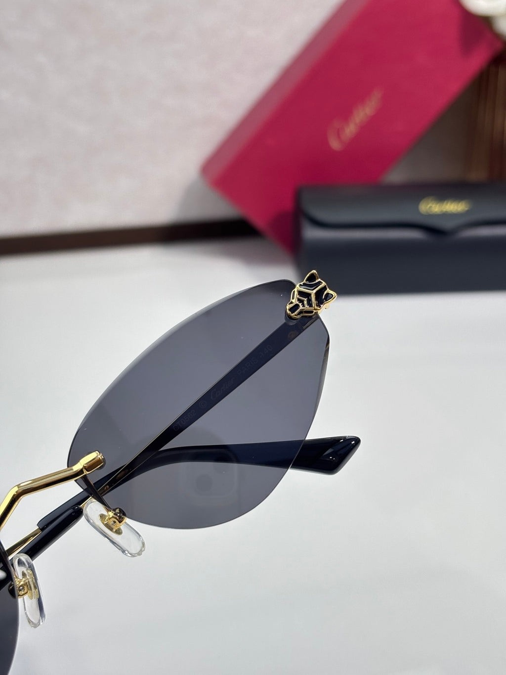 Gold-rim sunglasses close-up with dark blue gradient lens and decorative hinge