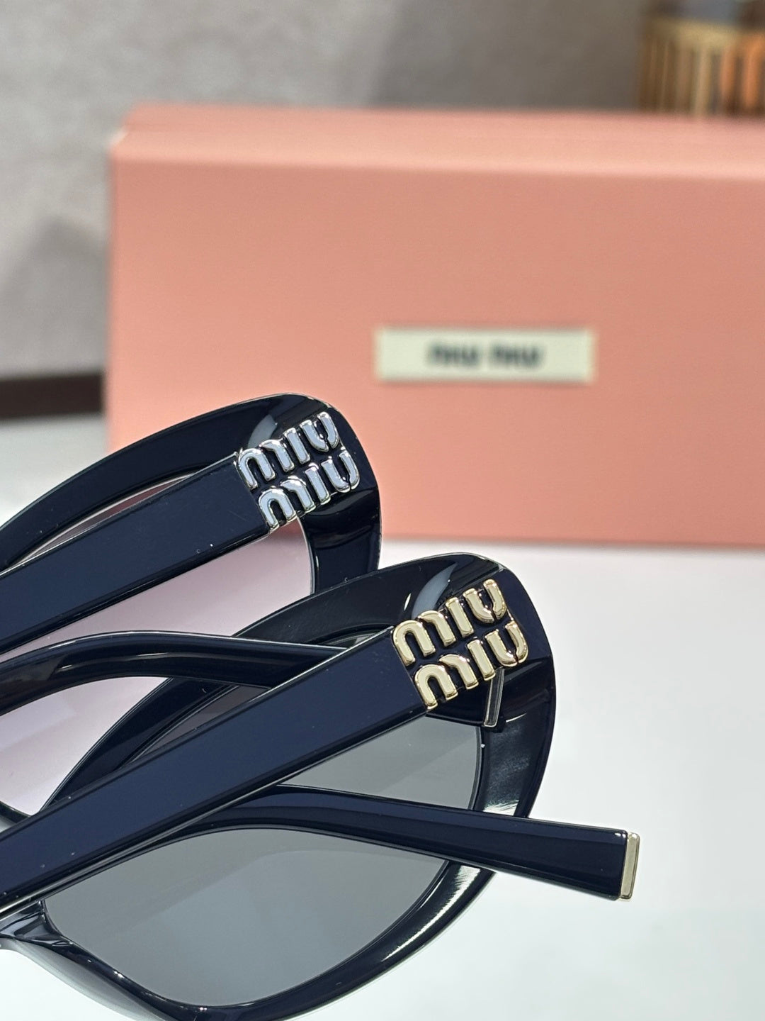 MiuMiu cat-eye sunglasses close-up with dark frame arms and embossed logo detail