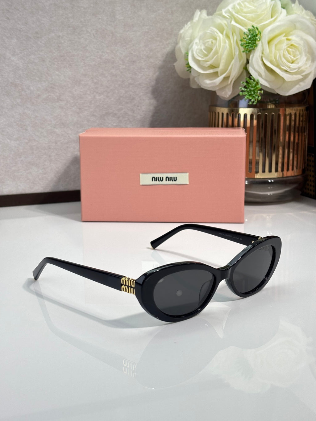 MiuMiu cat-eye sunglasses with dark frames and oval lenses, tilted on display