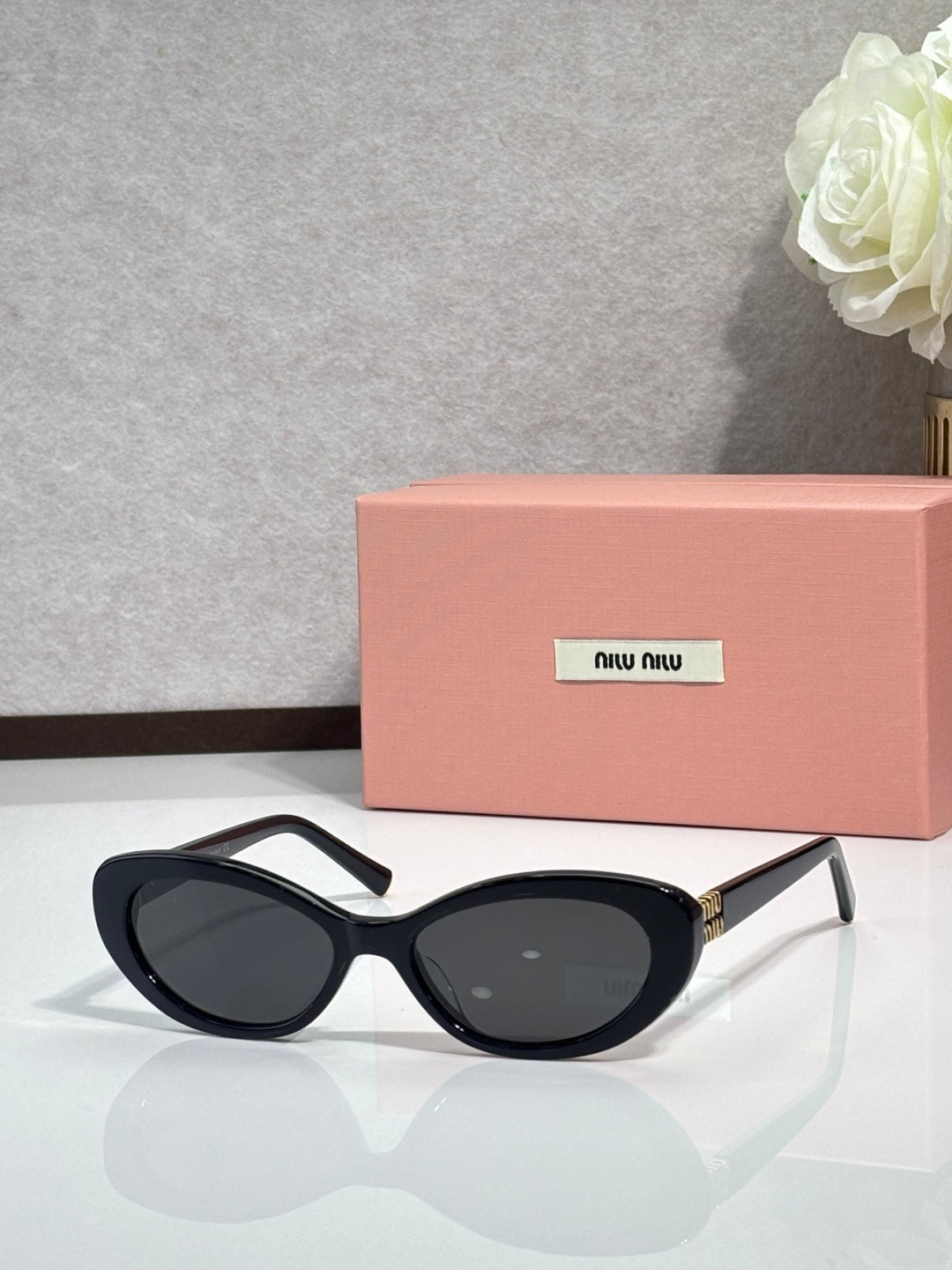 MiuMiu cat-eye sunglasses with dark frames and oval lenses, gold-tone hinges