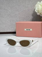 MiuMiu cat-eye sunglasses with white frames and dark oval lenses, gold-tone hinges