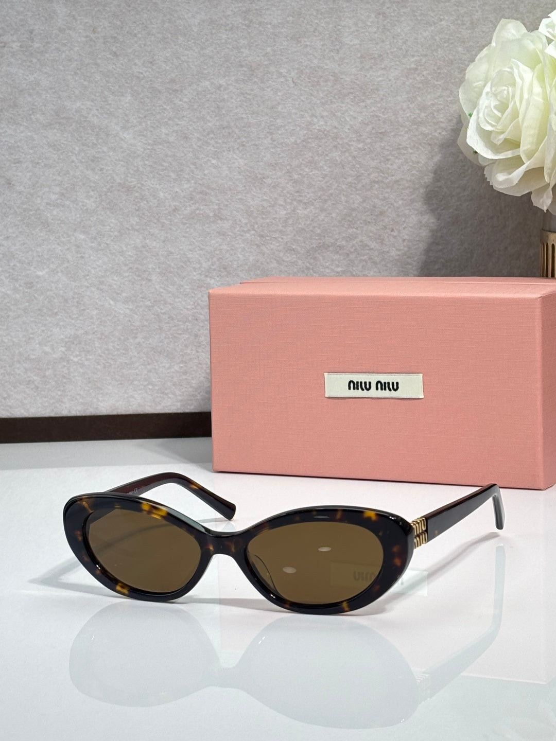 MiuMiu cat-eye sunglasses with dark frames and brown-tinted oval lenses, gold tips