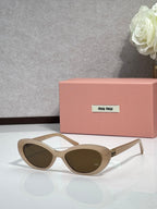 MiuMiu cat-eye sunglasses with beige frames and dark oval lenses, gold-tone details