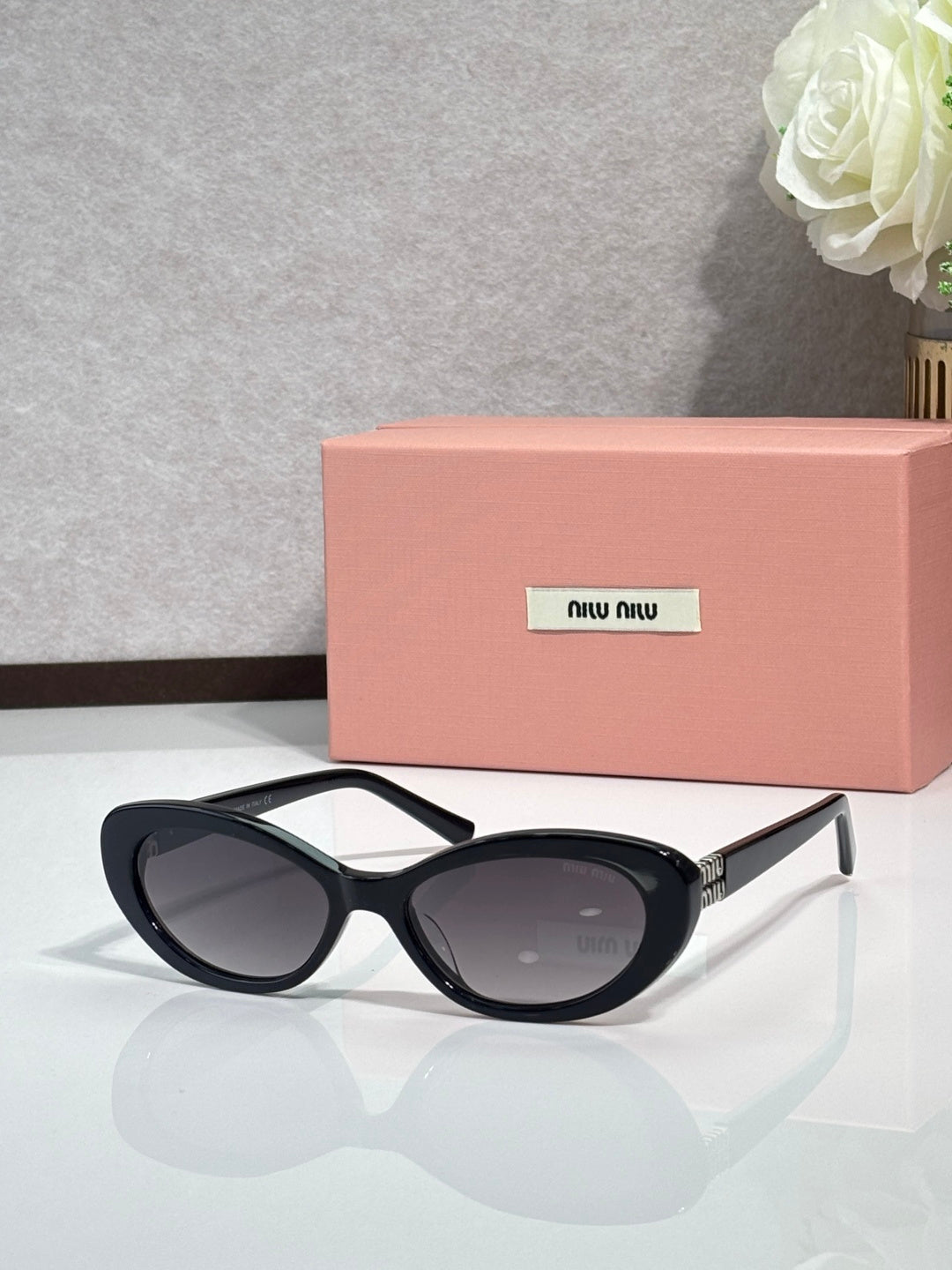 MiuMiu cat-eye sunglasses with dark frames and smoke-tinted oval lenses, gold accents