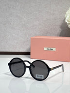 MiuMiu sunglasses with black round frames and dark lenses, logo on temple