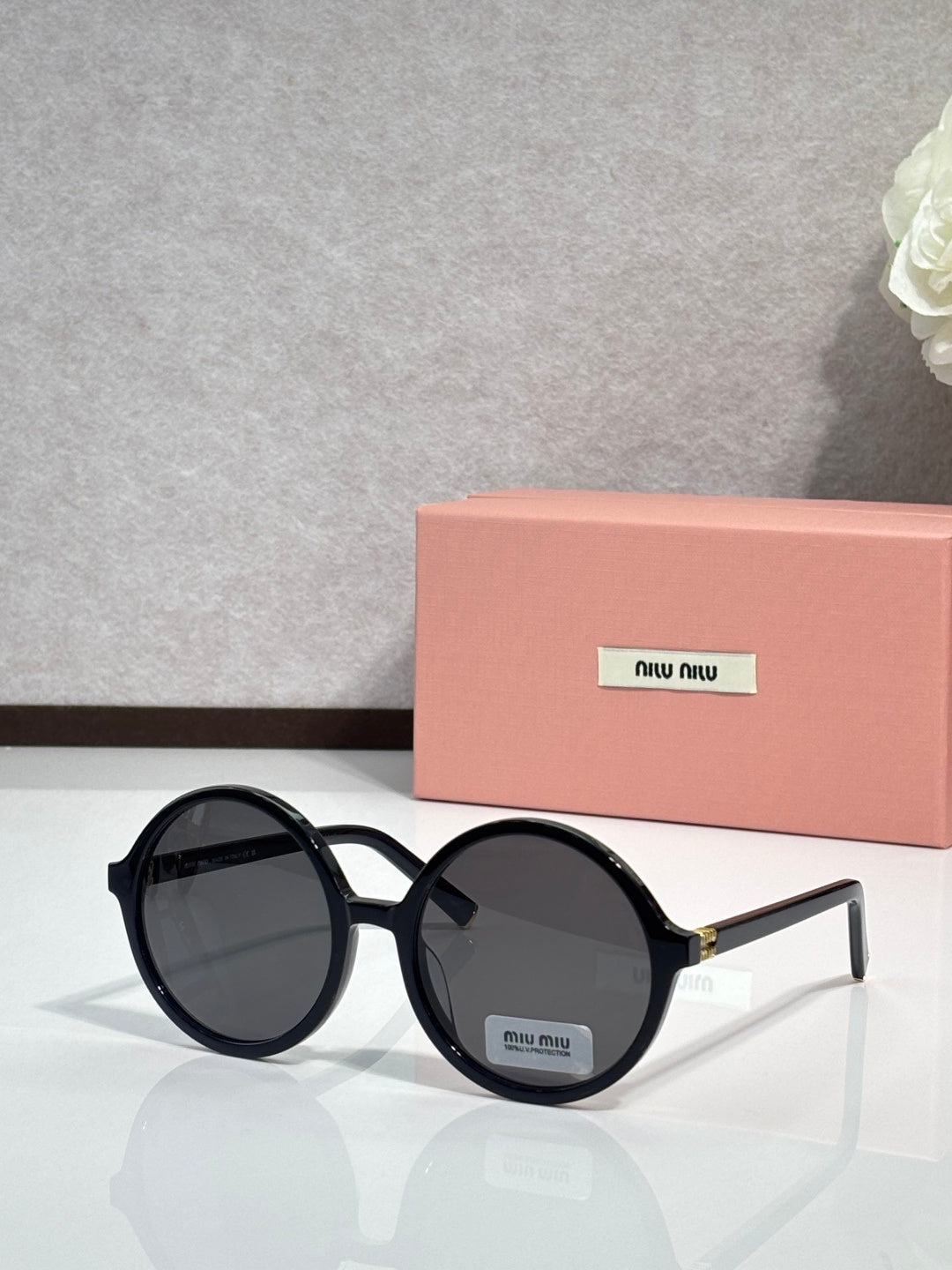 MiuMiu sunglasses with black round frames and dark lenses, logo on temple