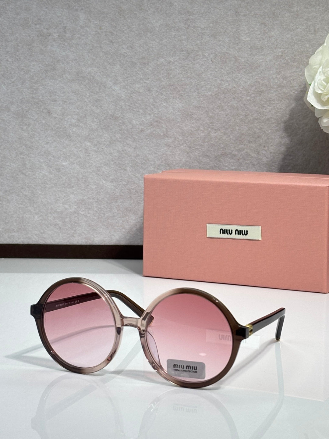 MiuMiu sunglasses with maroon round frames and pink tinted lenses, logo on lens