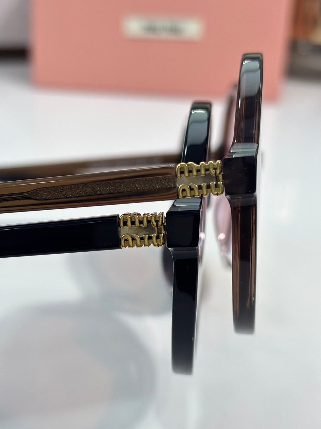 MiuMiu sunglasses close-up of black temple hinges with gold hardware
