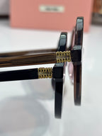 MiuMiu sunglasses close-up of black temple hinges with gold hardware