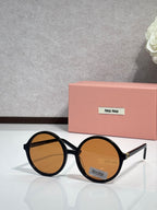 MiuMiu sunglasses with black round frames and amber tinted lenses, logo on lens