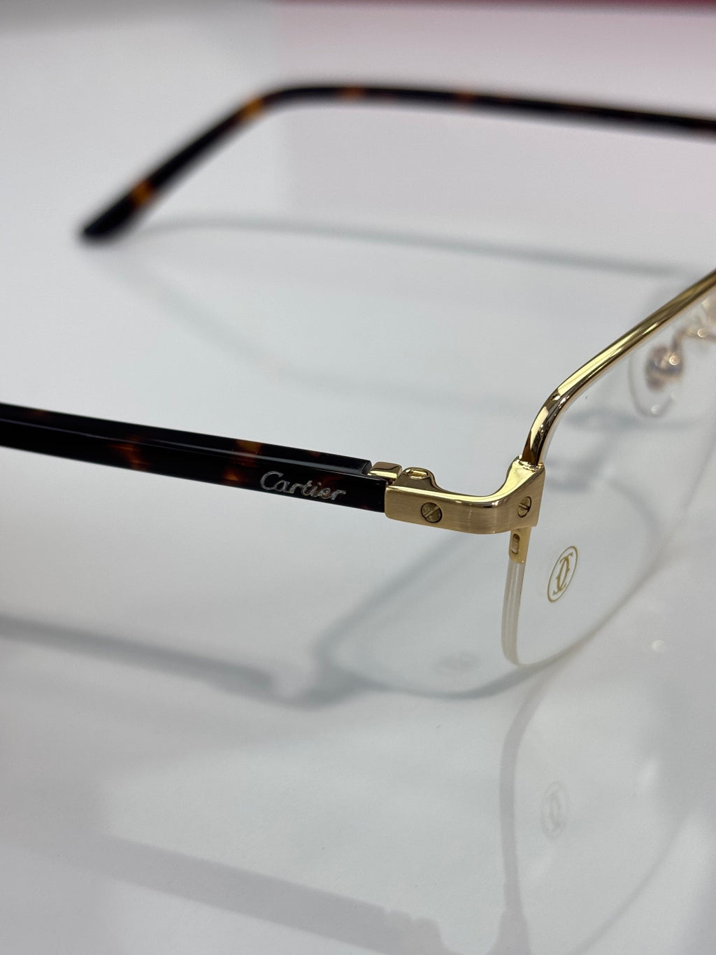 Cartier eyeglasses close-up: gold hinge and black temple, clear lenses