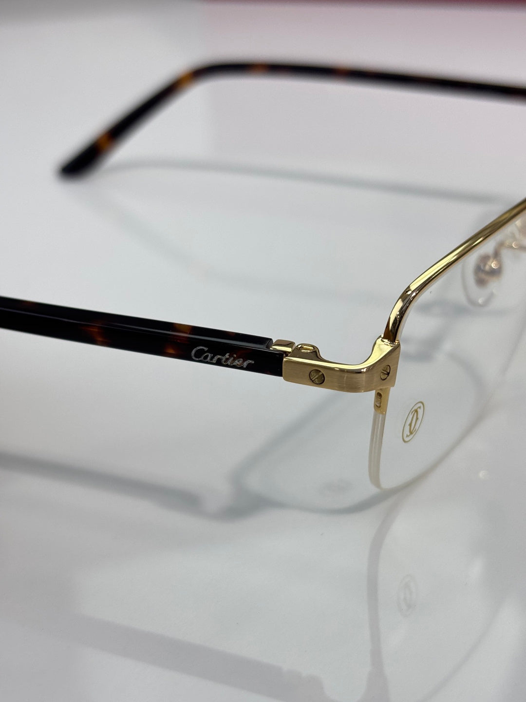 Cartier eyeglasses close-up: gold hinge and black temple, clear lenses