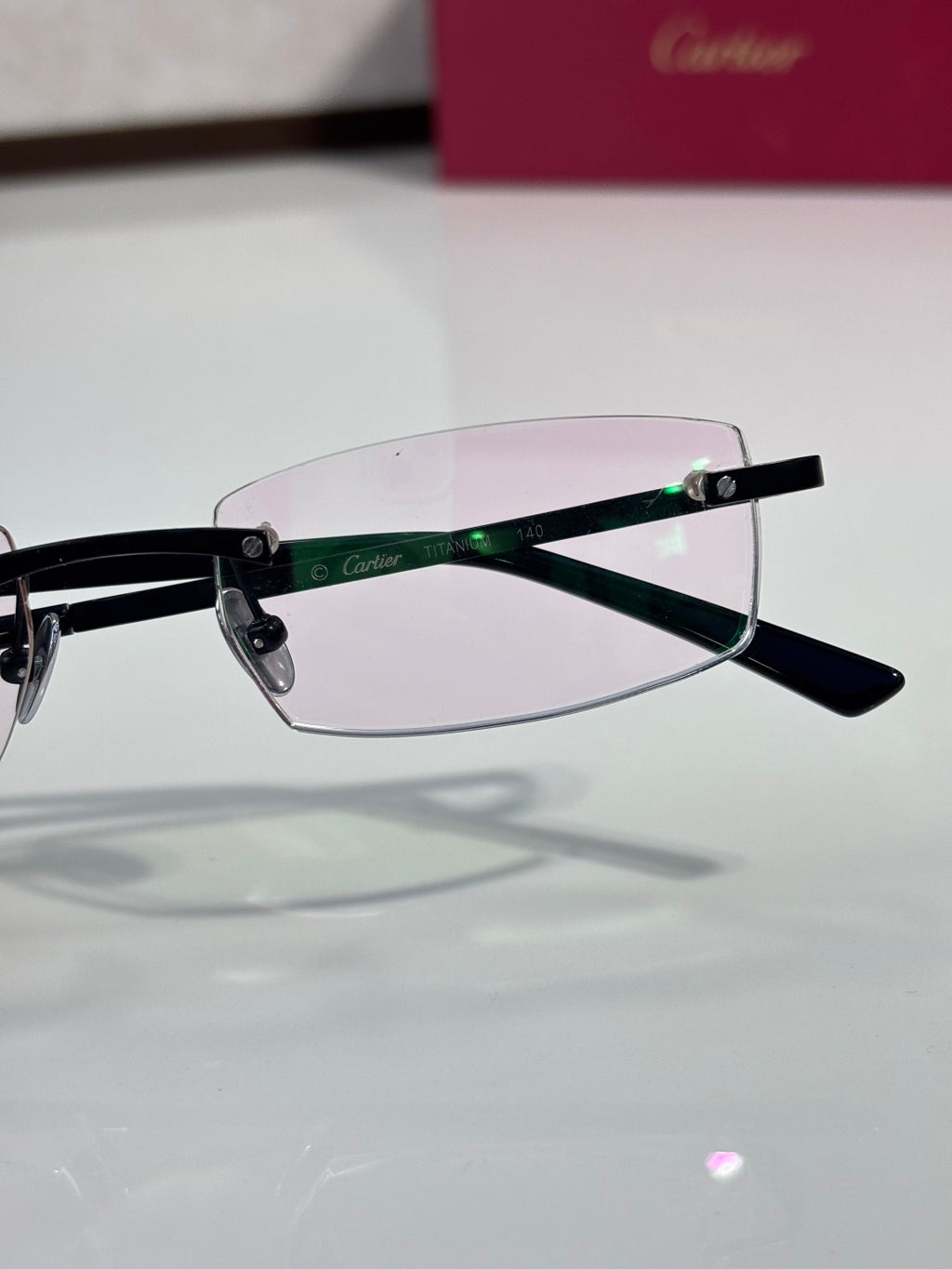 Cartier eyeglasses side view with black frame and clear lenses, light pink tint