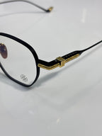 Close-up of black round eyeglasses with gold hinge and metal temple end.