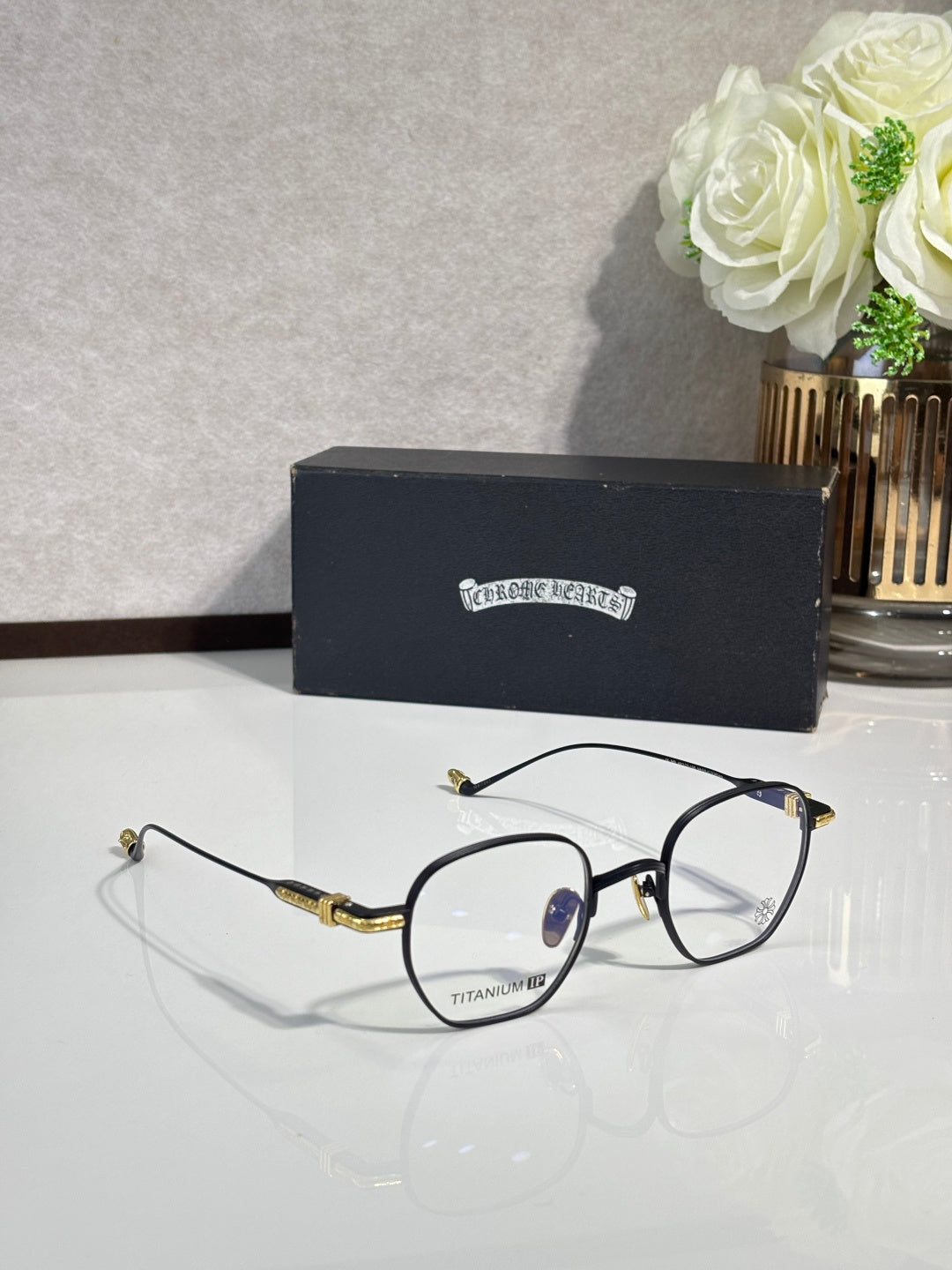 Black round eyeglasses with clear lenses and gold metal temple accents.