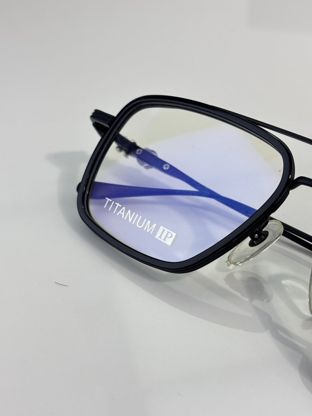 Close-up of blue-striped eyeglass bridge with black frame and clear lens.