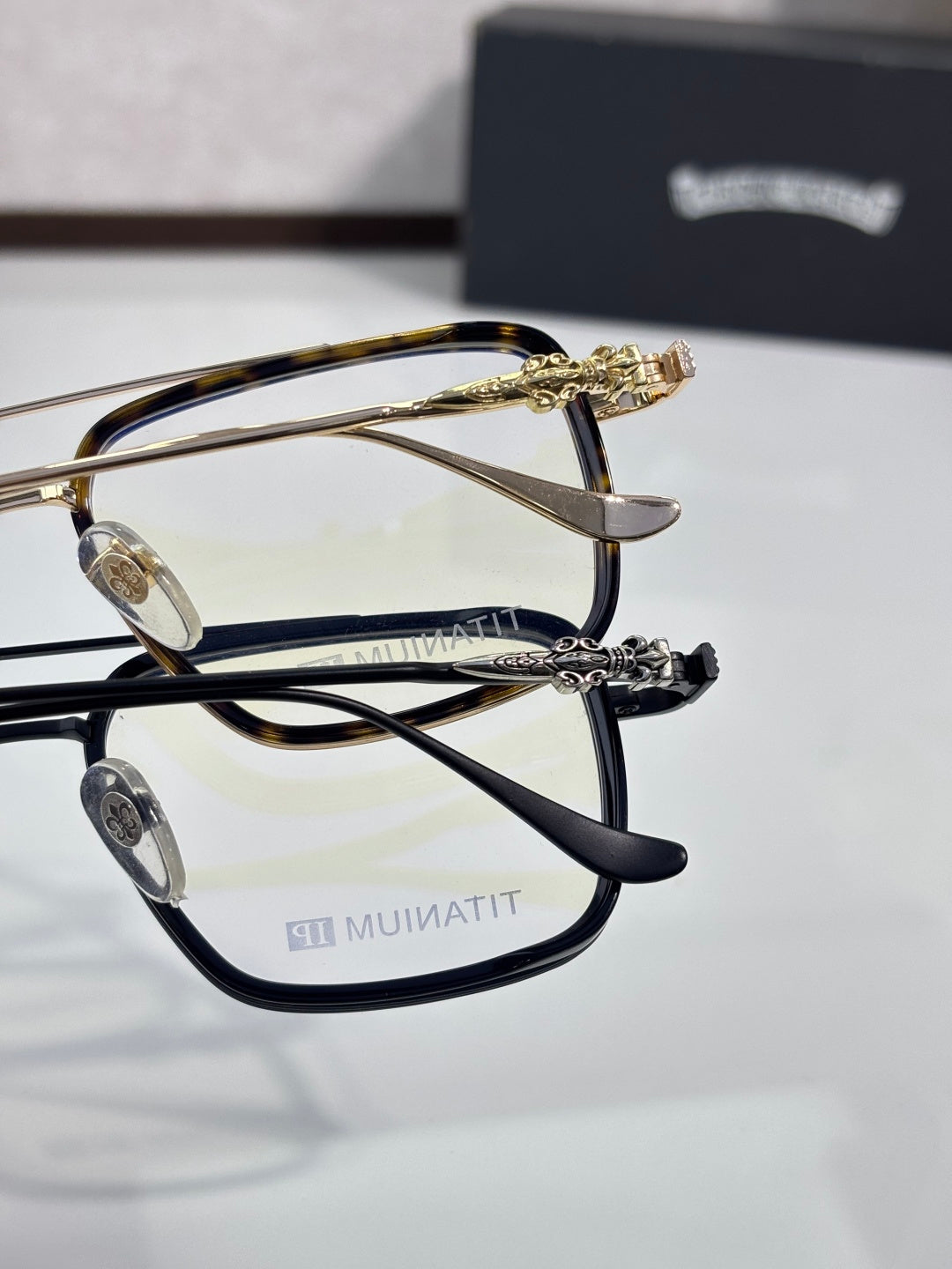 Close-up of gold-and-black eyeglass frames with ornate metal temple details.