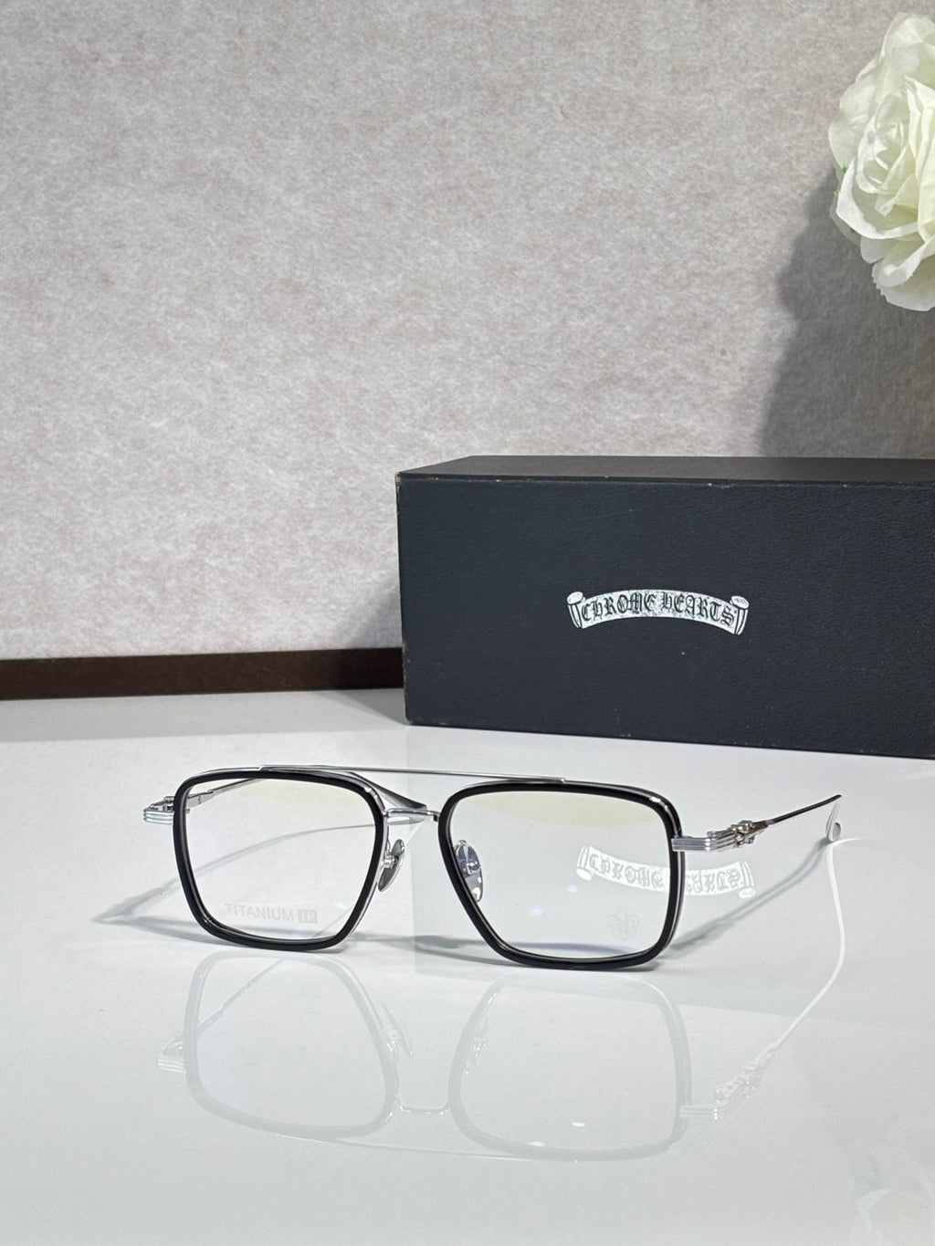 Black rectangular eyeglasses with clear lenses and visible blue hinge detail.