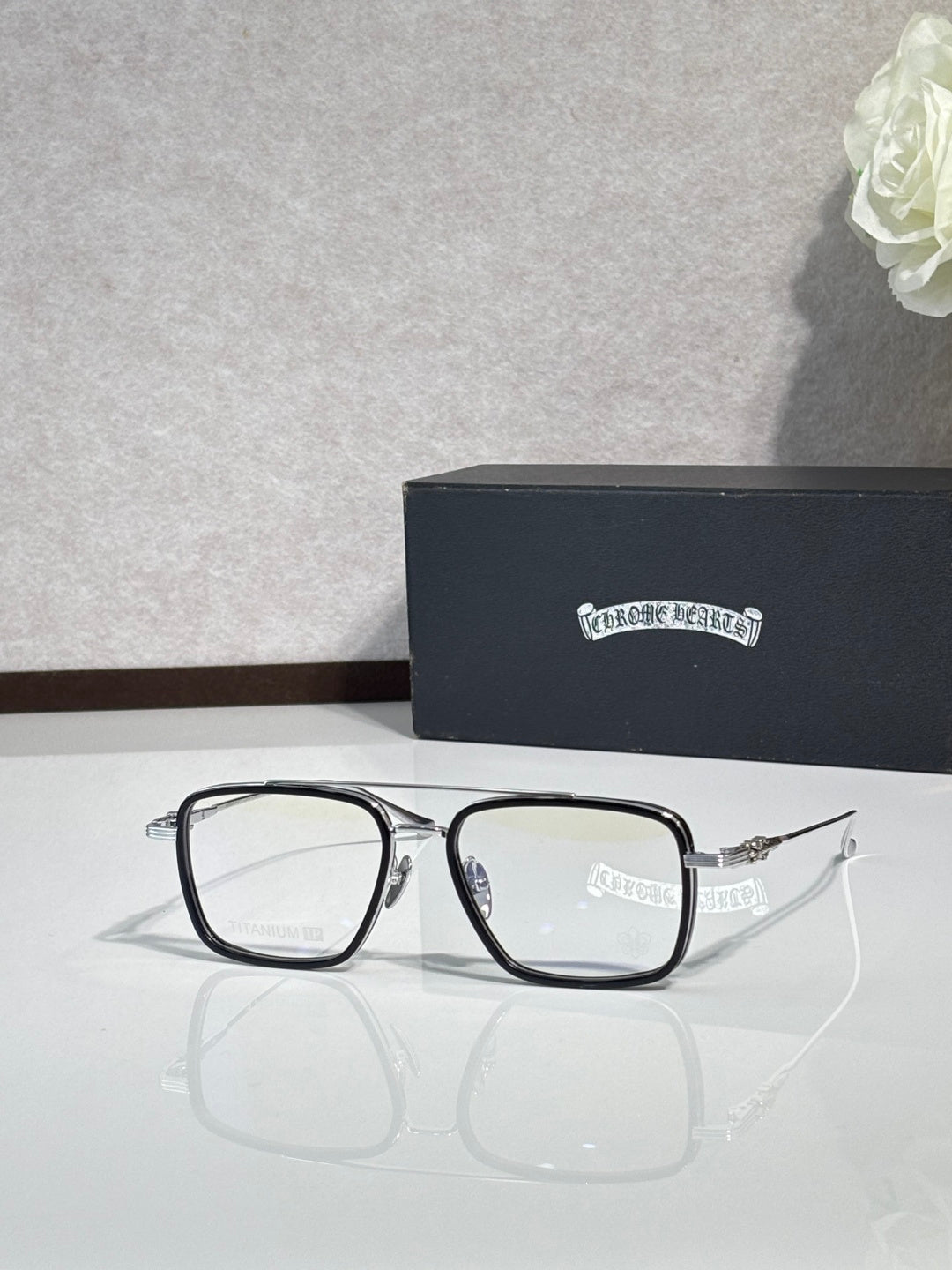 Black rectangular eyeglasses with clear lenses and visible blue hinge detail.