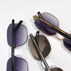 Overlapping sunglasses in gold and black frames with purple tinted lenses.