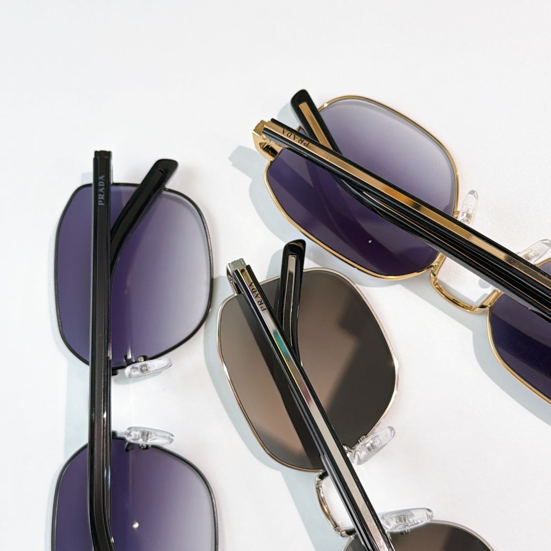 Overlapping sunglasses in gold and black frames with purple tinted lenses.