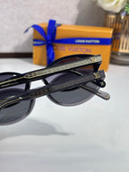 Louis Vuitton sunglasses close-up, black frame with gold-patterned temples and dark lenses
