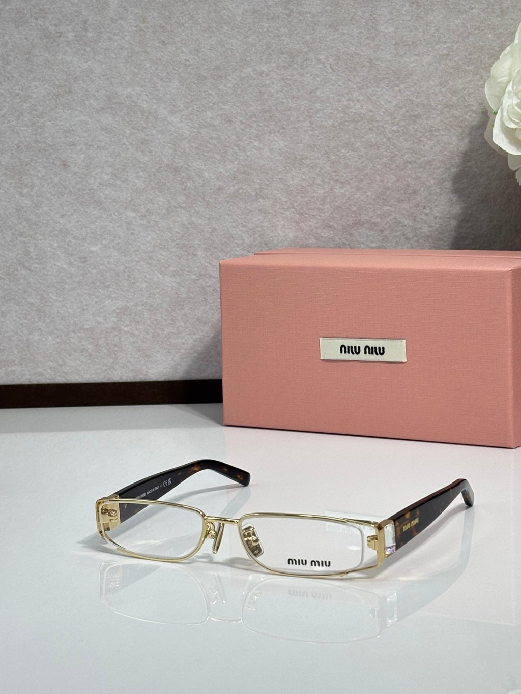 MiuMiu gold eyeglass frame with black temples and clear lenses