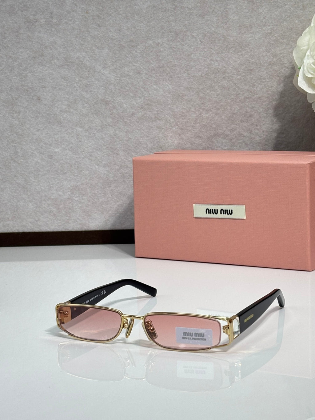 MiuMiu gold eyeglass frame with black temples and pink-tinted lenses