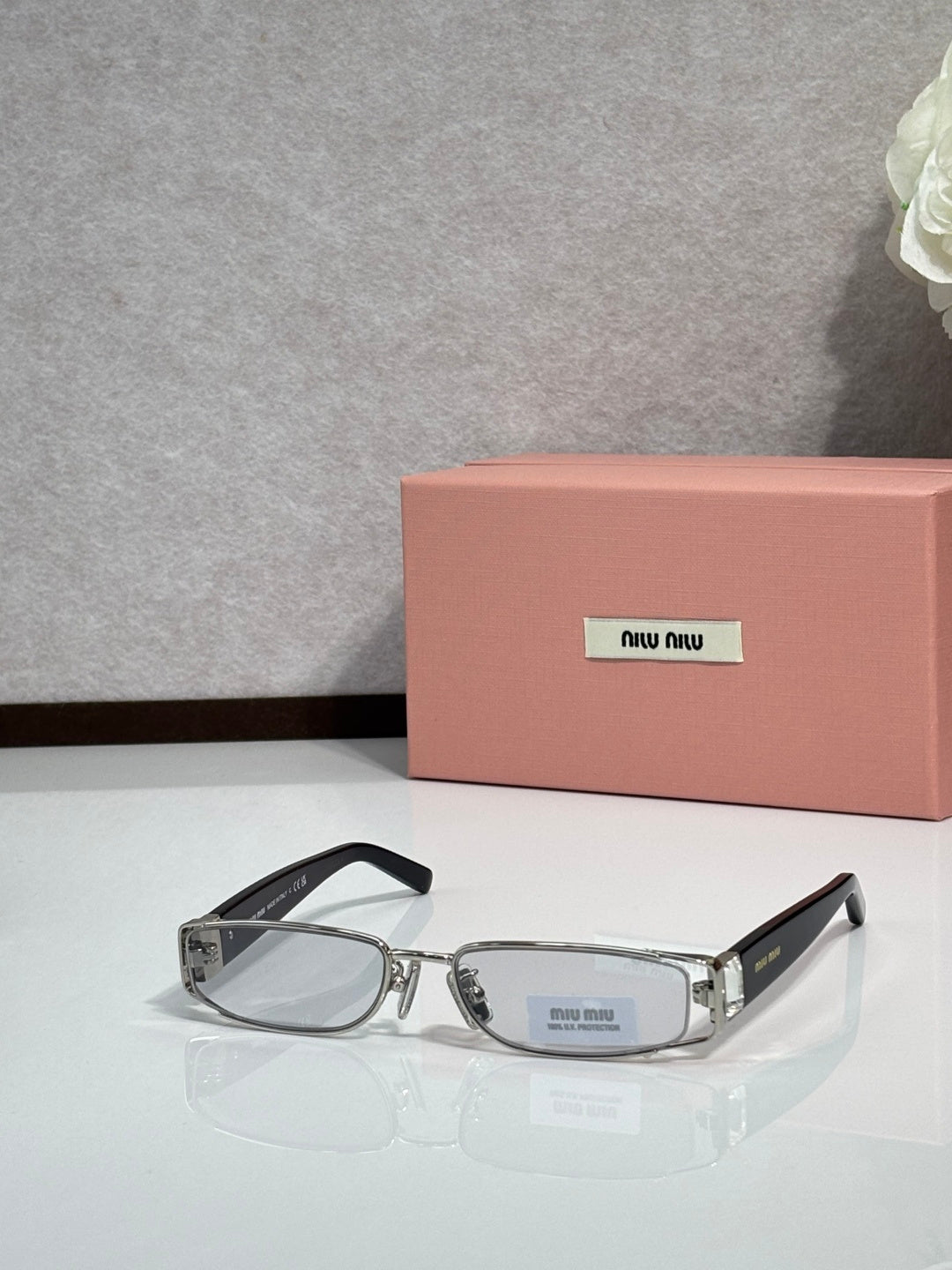 MiuMiu silver eyeglass frame with black temples and light gray lenses