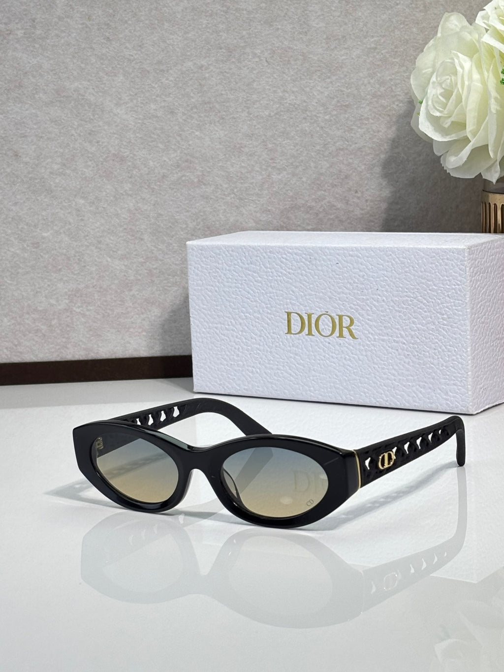 Dior sunglasses with black oval frames, gold temple details, and tinted lenses