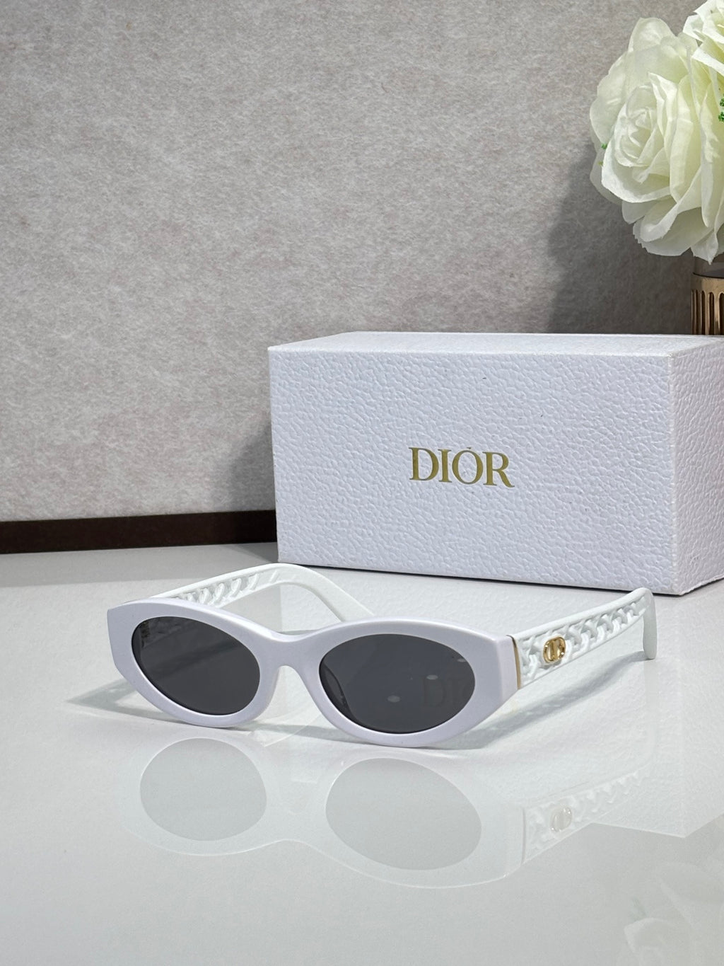 Dior sunglasses with white oval frames and dark tinted lenses