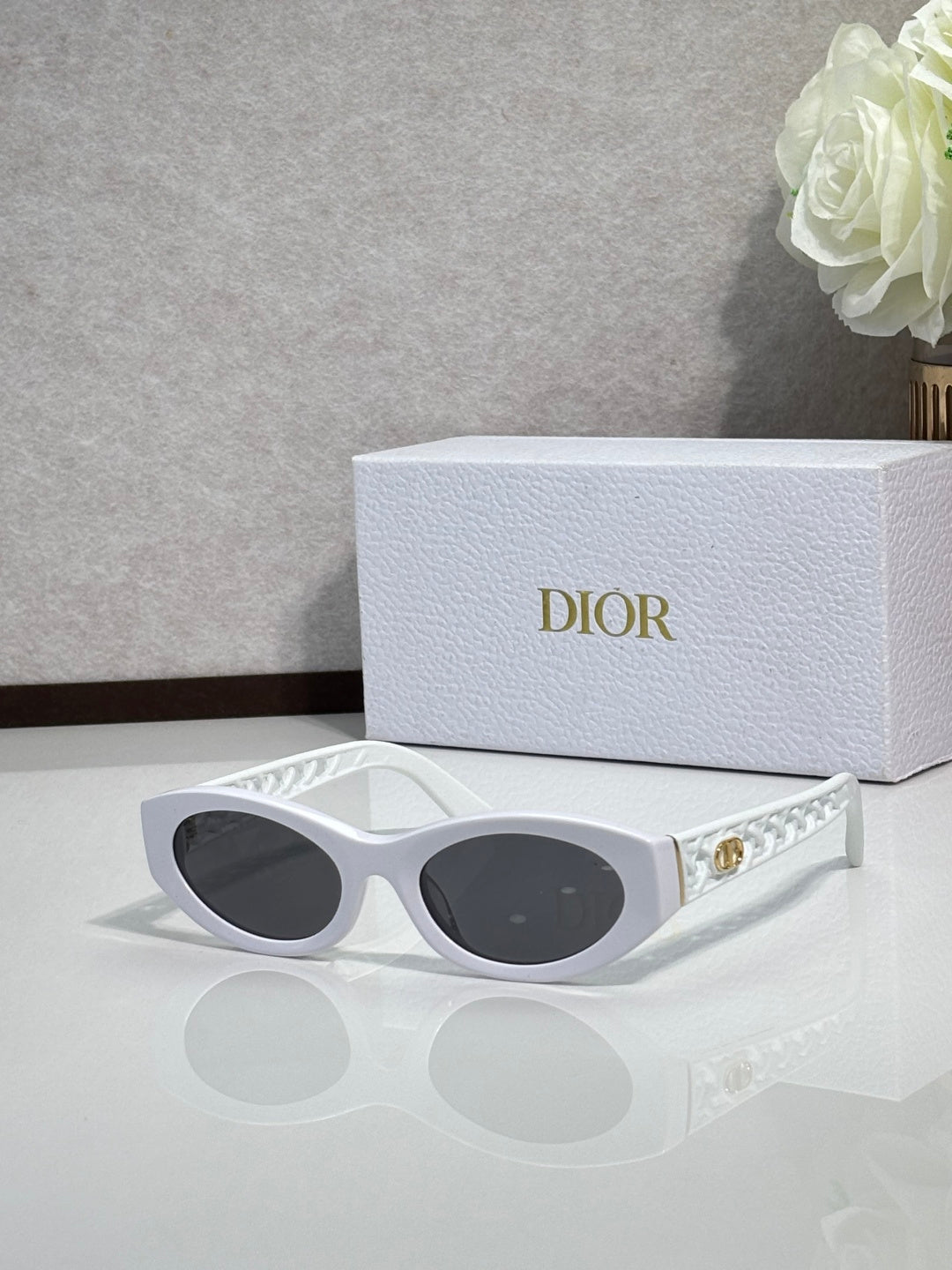 Dior sunglasses with white oval frames and dark tinted lenses