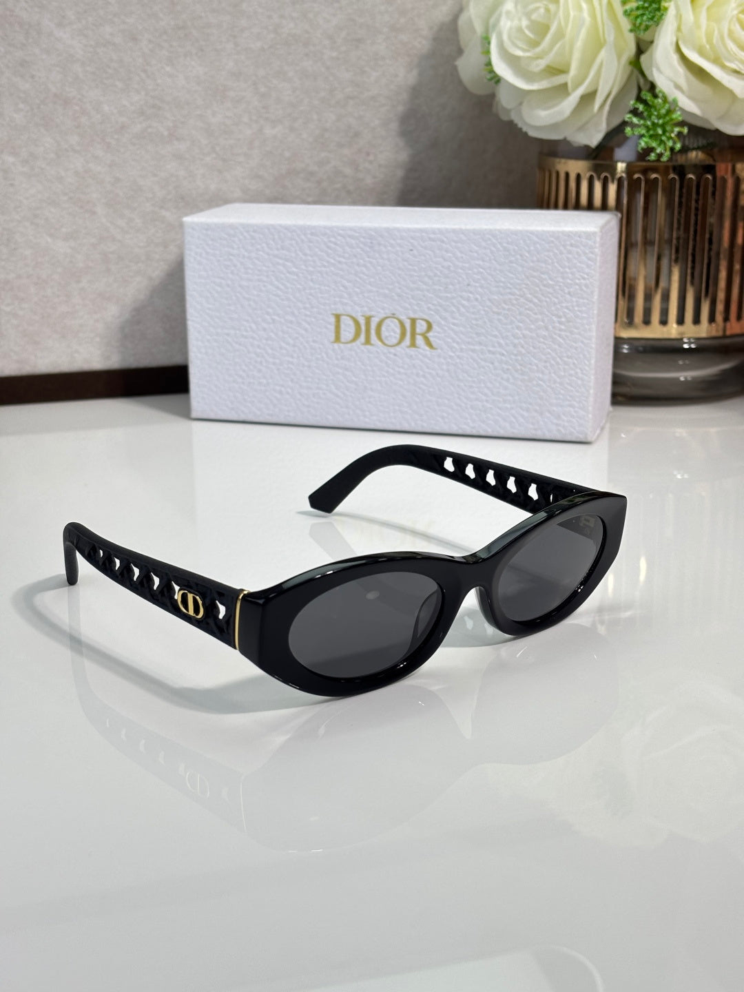 Dior sunglasses with black oval frames and dark lenses, gold accents