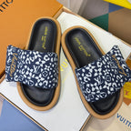 Louis Vuitton slide sandals with navy-and-white monogram straps and black footbeds, tan soles