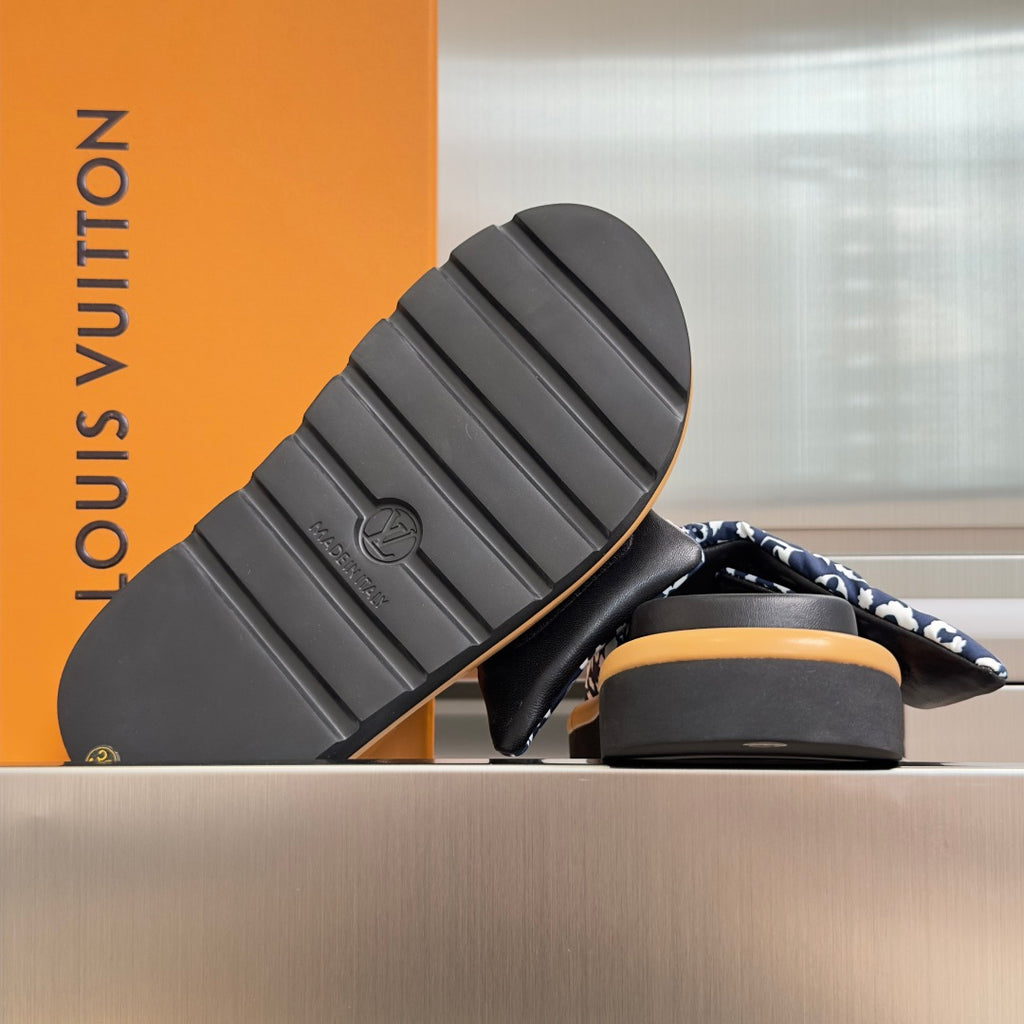 Louis Vuitton sandal outsole view: black tread with embossed logo, tan-banded base