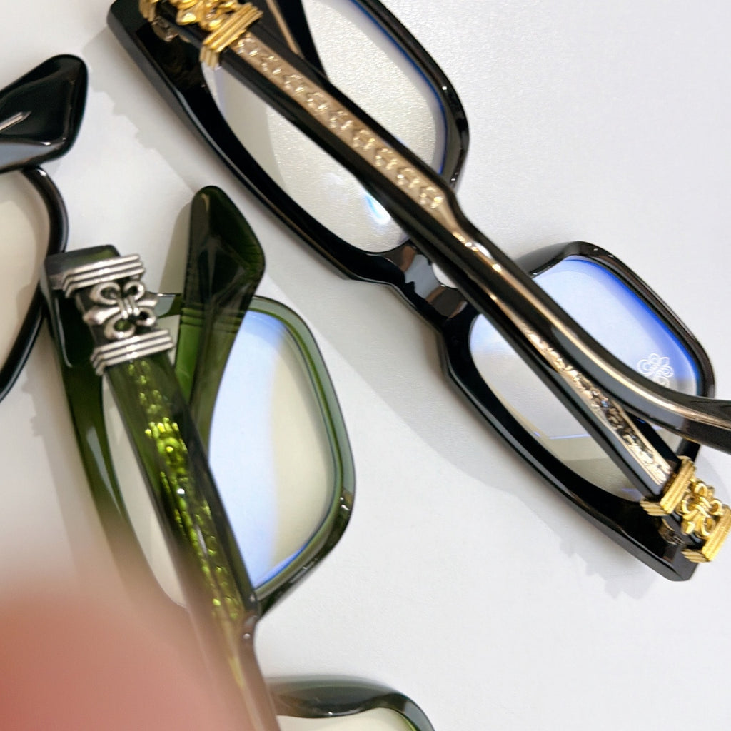 Black chrome eyeglasses close-up with gold-tone stripe and blue-tinted lens