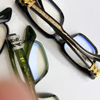 Black chrome eyeglasses close-up with gold-tone stripe and blue-tinted lens