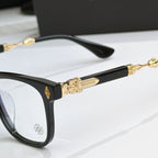 Black eyeglass frames close-up with gold temple barwork and flower emblem on front