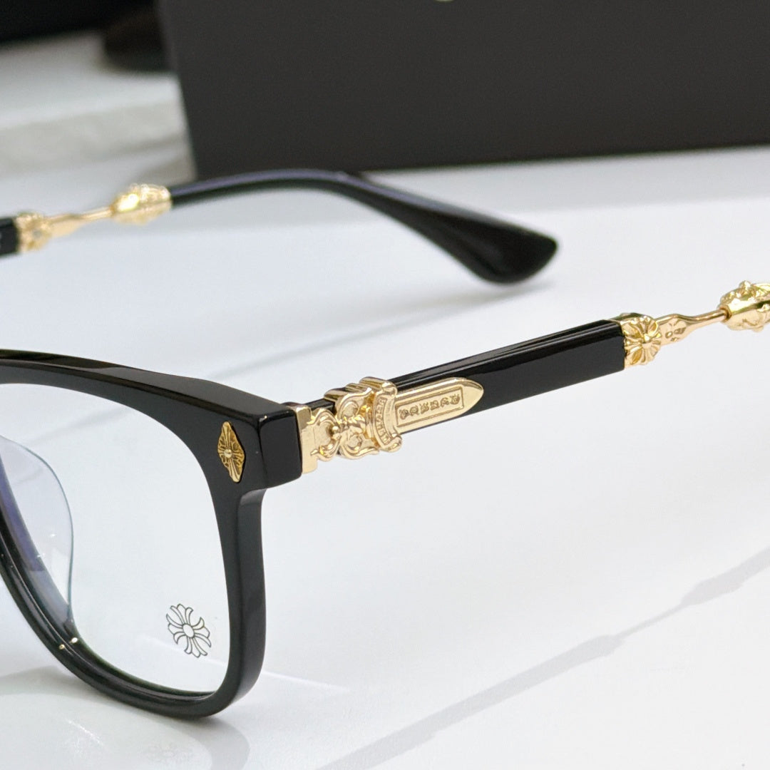 Black eyeglass frames close-up with gold temple barwork and flower emblem on front